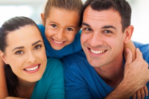 cute family of three face closeup portrait at home